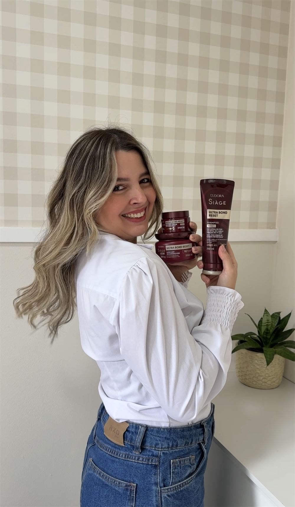 Yasmin Carreira sorrindo e segurando produtos de cabelo Eudora Siàge